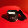 Candle in a 'Midnight Architect' container on a red background