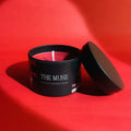 Black candle container labeled 'The Muse' on a red background - BTS 